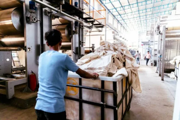 Un hombre llevando un carrito lleno de trapo industrial